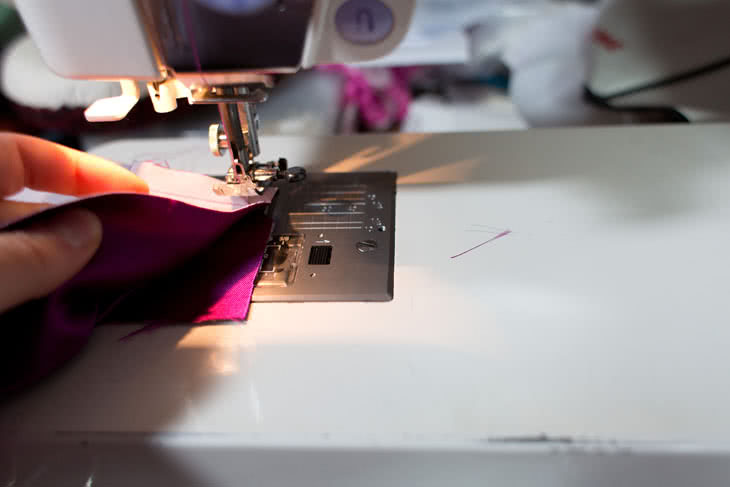 Now you're going to take the folded edge of the fabric and pivot it out of the way to the left while keeping the bottom layer of fabric in place. Your goal is to get the raw edge of the long folded edge of the fabric aligned with that bottom layer. There will be a little tiny fold you'll have to sew over, but if you cut the corner enough it will be minimal. 