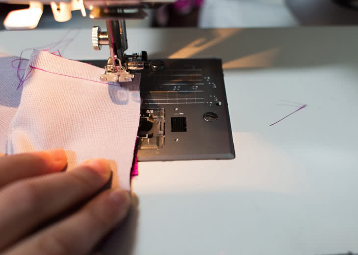 Now you're going to take the folded edge of the fabric and pivot it out of the way to the left while keeping the bottom layer of fabric in place. Your goal is to get the raw edge of the long folded edge of the fabric aligned with that bottom layer. There will be a little tiny fold you'll have to sew over, but if you cut the corner enough it will be minimal. 