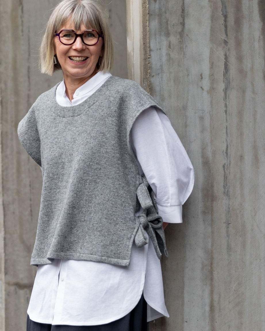 Rumi Woven Top in grey, layered over a white shirt, showing its round neckline and side ties.