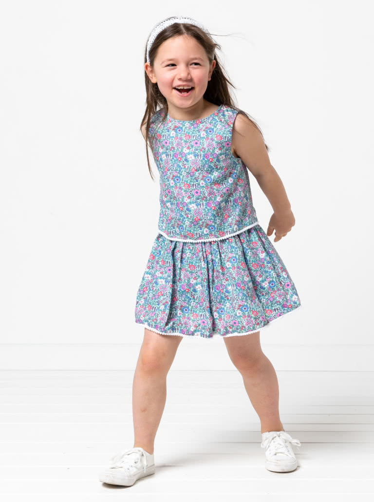 Victoria Kids Woven Dress By Style Arc - Easy-fit dress featuring a bodice overlay, elastic waist, and a gathered skirt, elegantly finished with a back neck button, for Kids 02-14