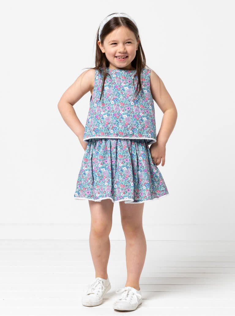 Victoria Kids Woven Dress By Style Arc - Easy-fit dress featuring a bodice overlay, elastic waist, and a gathered skirt, elegantly finished with a back neck button, for Kids 02-14
